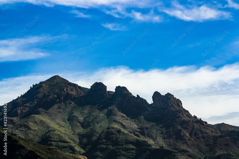 Montaña volcánica con cielo azul y nubes en el sur de la isla de Tenerife, Islas Canarias, España. Paisaje escarpado de los picos de la cresta de una montaña con un cielo azul con nubes.
