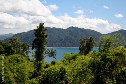 Nosy Be Island and its mountains covered with green vegetation seen from the Nosy Komba jungle with the Indian Ocean in the middle. View of Lokobe Reserve and the white sand line of the coast. photo