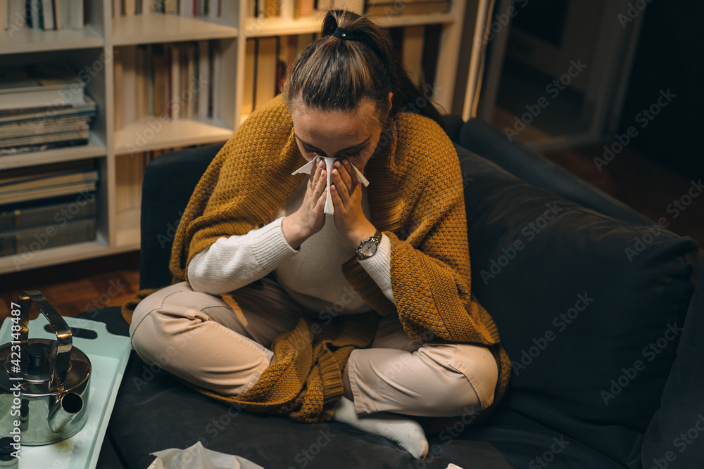 woman sitting at home and blowing her nose. she catch a cold. coronavirus concept