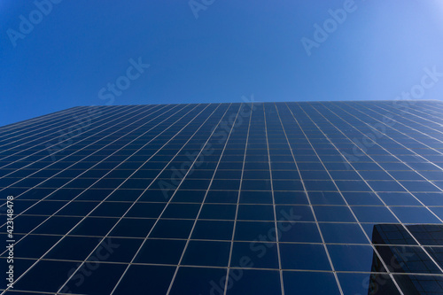View from below of the panes of a building and the clear blue sky