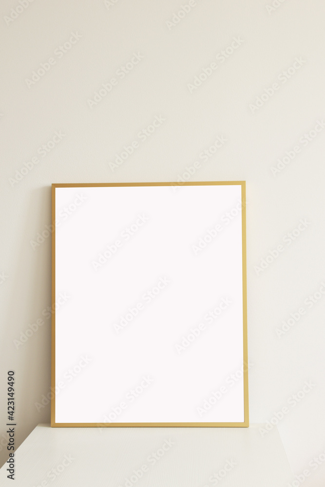 empty minimal style golden vertical frame on white table with white wall on the background empty minimal style golden vertical frame on white table with white wall on the background