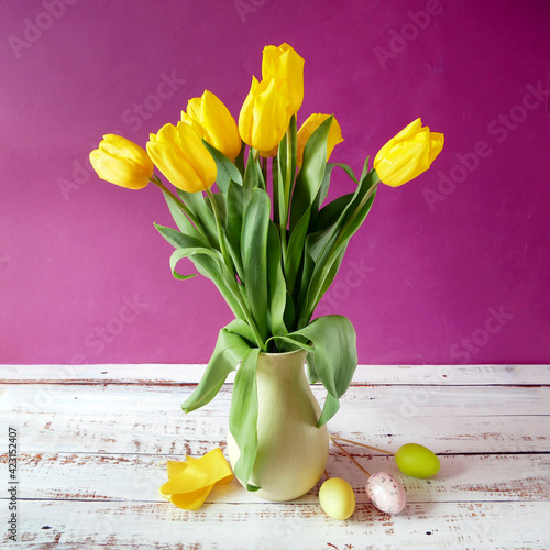 yellow tulips and eatser eggs on wooden background, still life photo