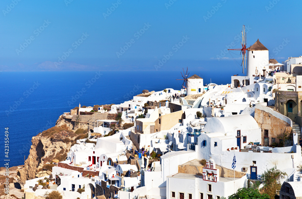 Picturesque village of Oia with white traditional Cycladic houses on narrow streets and windmills on a hill, Santorini, Greece