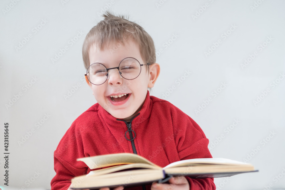 Cute Cheerful Little boy reading a book in glasses. Smart preschooler. Back to school concept Cute Cheerful Little boy reading a book in glasses. Smart preschooler. Back to school concept