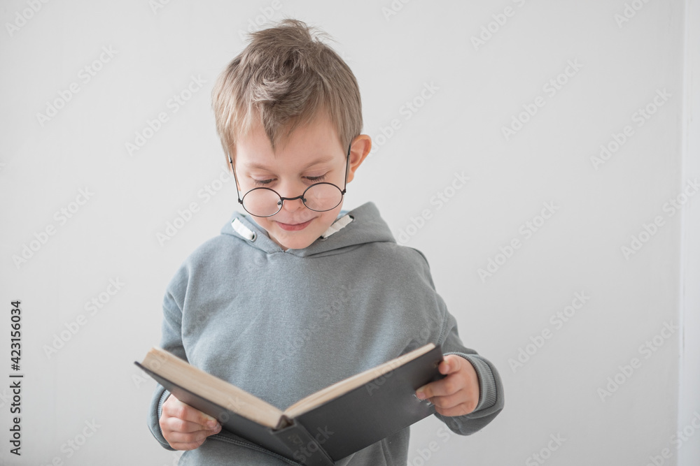 Cute Cheerful Little boy reading a book in glasses. Smart preschooler. Back to school concept Cute Cheerful Little boy reading a book in glasses. Smart preschooler. Back to school concept