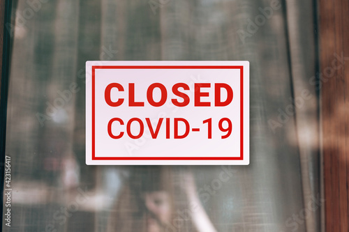 Signboard saying Closed due to Covid-19 at the front door glass. Coronavirus outbreak lockdown