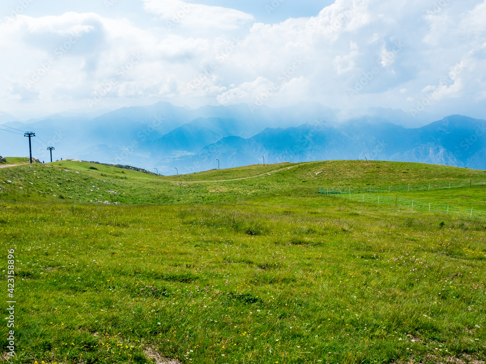 The view is over the mountains of Monte Baldo in Malcesine in Italy in a green meadow.