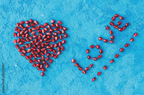 word love and heart made from pomegranate seeds on a blue textural background.