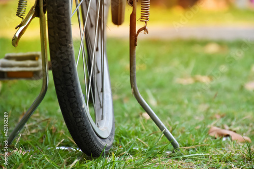 The rear wheel of the bicycle is parked by the road and is deformed because it has got accident and has been used for a long time. Soft focus photo