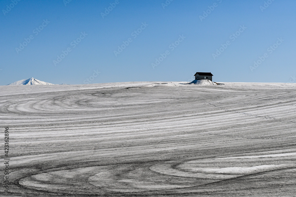 Fototapeta premium 3月の美瑛町 融雪剤がまかれた丘と小屋のある風景