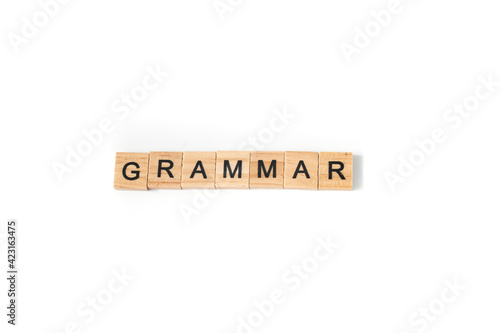 Top view of pen and word grammar made of square wooden tiles with the English alphabet scattered on a white background with space for text. The concept of thinking development, grammar.