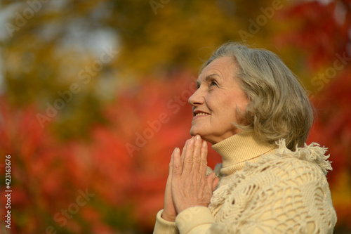 Senior smiling woman in park praying