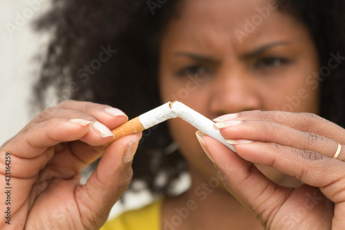 African american woman with afro hair and yellow t-shirt breaking a cigarette with her hands. photo