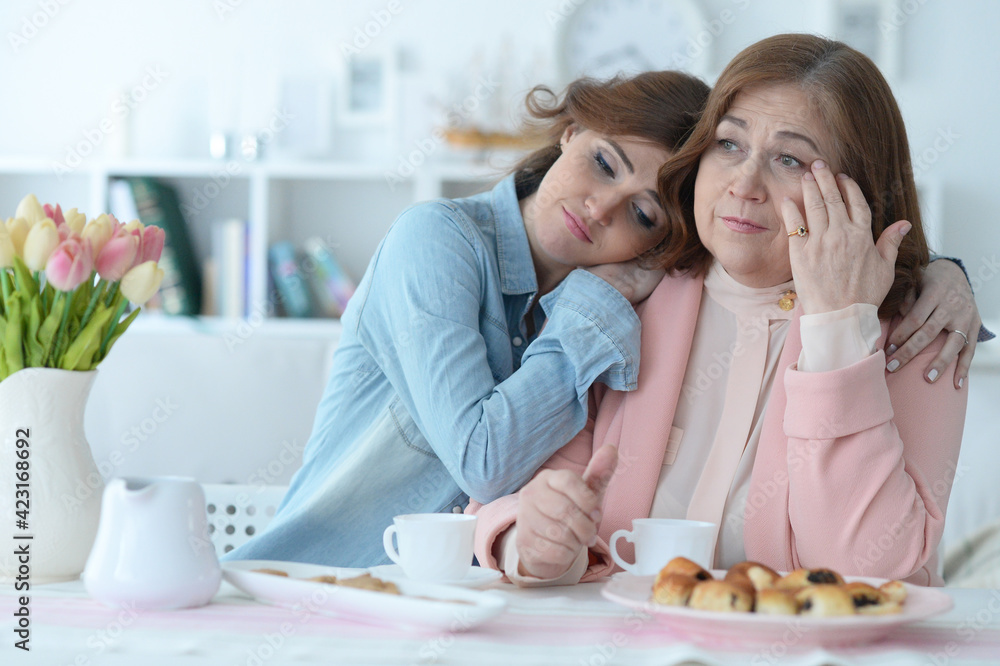 Mature woman talking with adult daughter while drinking tea Mature woman talking with adult daughter while drinking tea