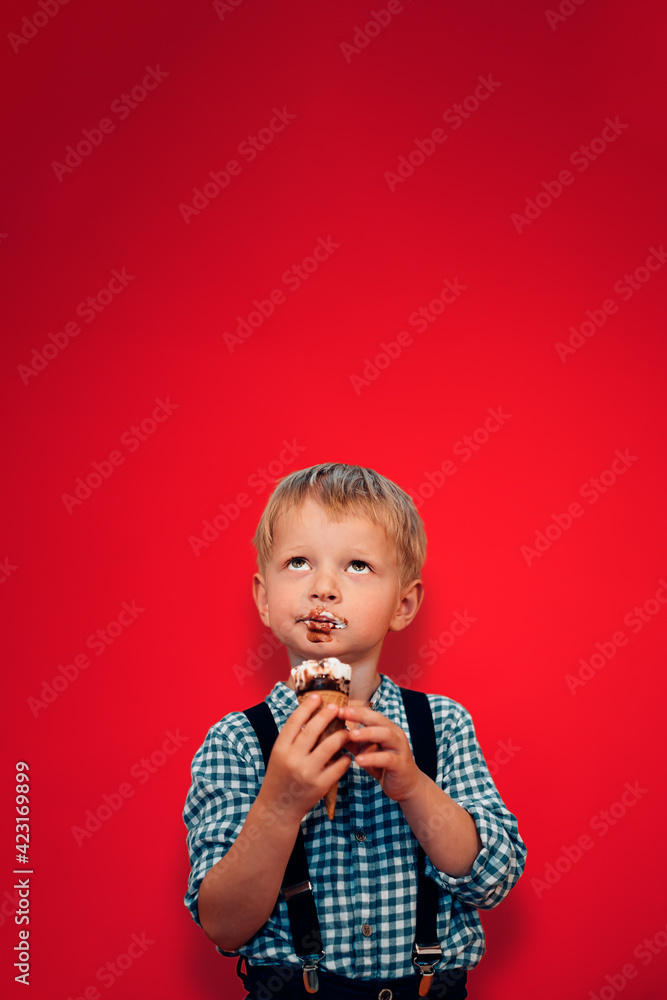 portrait of young blond caucasian hipster, mormon style child eating ice cream with a smeared mouth on vivid red background portrait of young blond caucasian hipster, mormon style child eating ice cream with a smeared mouth on vivid red background