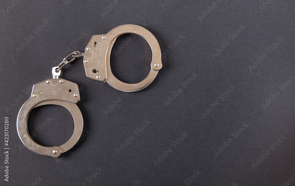 Metal handcuffs on an isolated black background.