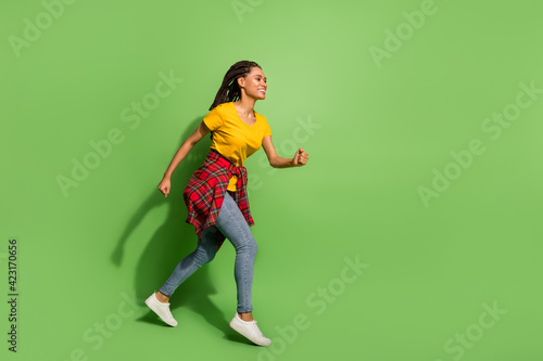 Full length body size view of lovely cheerful girl jumping running fast having fun isolated over bright green color background