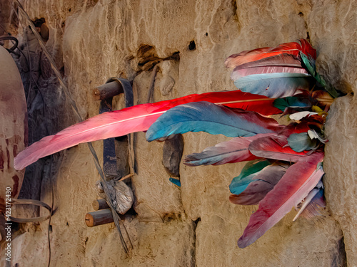 Nature morte, élément graphique composé de plumes de couleurs bleu rouge encastré emboîté assemblé enchâssé enclavé enfoncé Inséré dans un mur brun clair