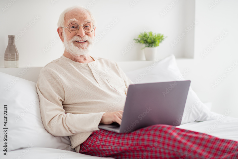 Photo of elderly man happy positive smile sit bed house wear pajamas chat type email browse internet laptop Photo of elderly man happy positive smile sit bed house wear pajamas chat type email browse internet laptop