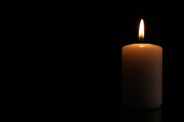 Burning candle on dark background, space for text. Memory day