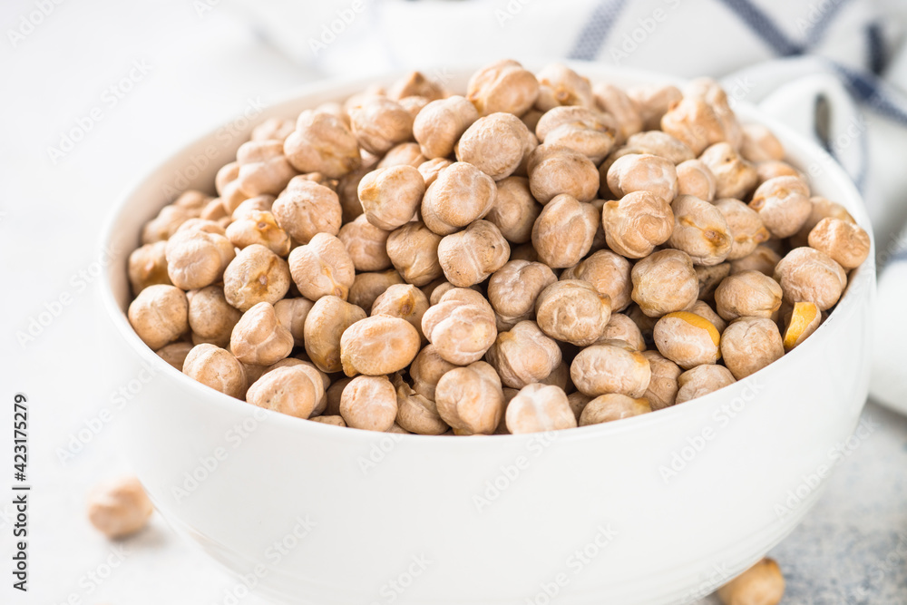 Chickpeas in white bowl at light kitchen table.