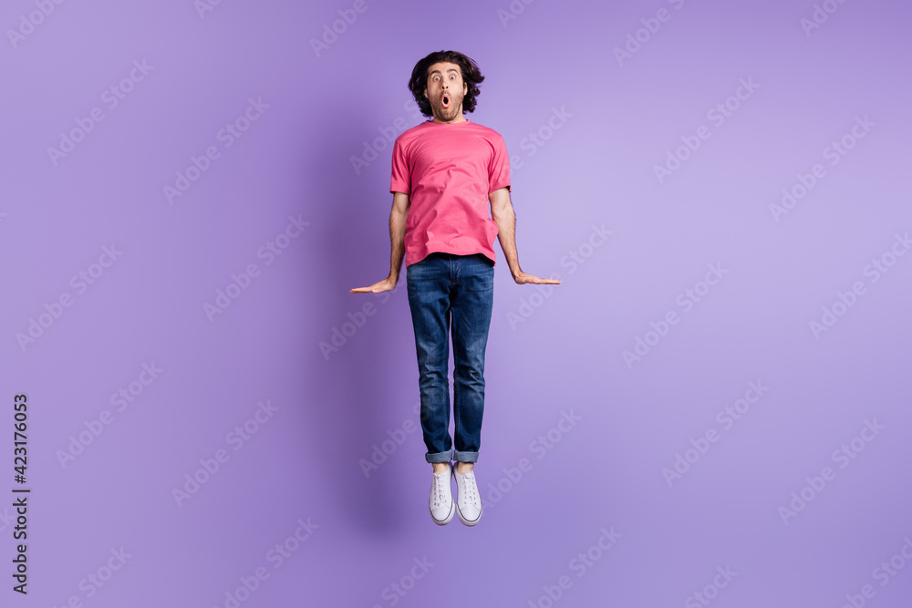 Full size photo of impressed nice brunet guy jump wear pink t-shirt jeans isolated on violet background