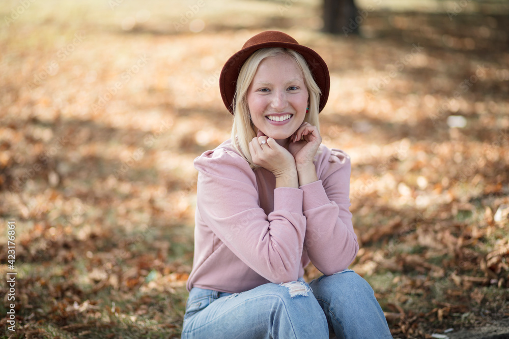 Young smiling blond woman sitting in park. Young smiling blond woman sitting in park.