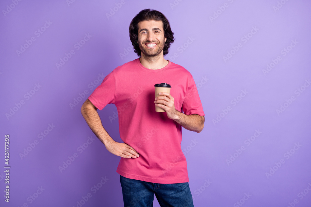 Photo of optimistic nice brunet guy hold cup wear pink t-shirt isolated on pastel violet color background Photo of optimistic nice brunet guy hold cup wear pink t-shirt isolated on pastel violet color background