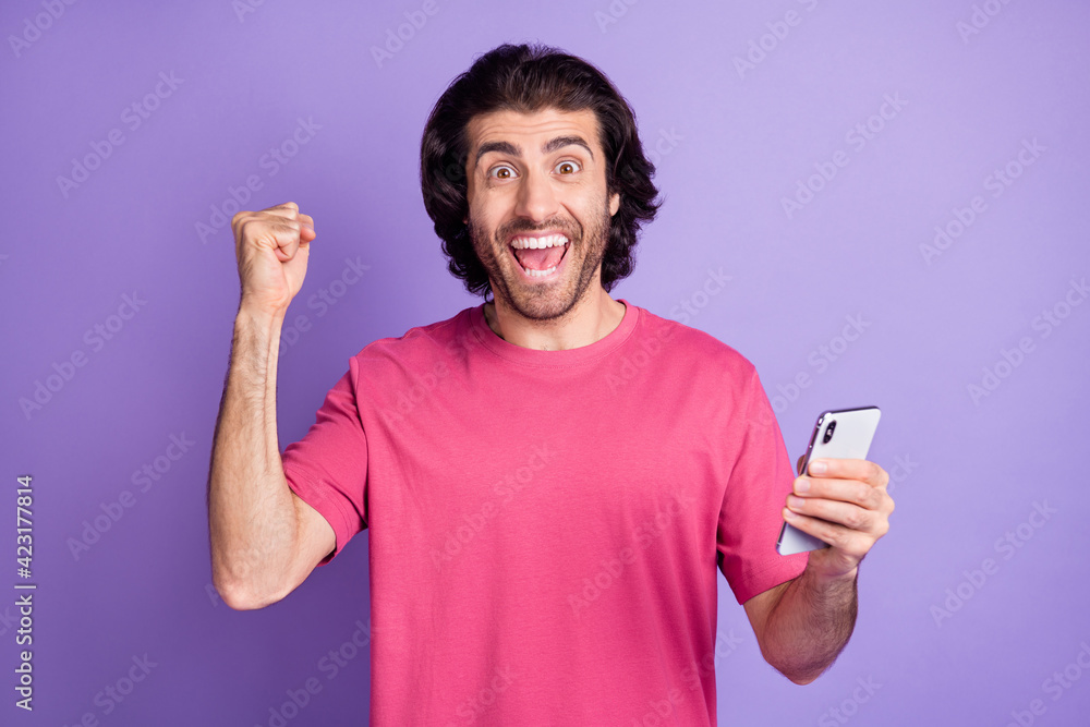 Photo of lucky funny young guy dressed pink outfit chatting modern gadget isolated purple color background Photo of lucky funny young guy dressed pink outfit chatting modern gadget isolated purple color background