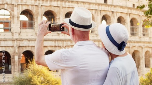 Family of senior travelers enjoy vacation in Rome. Seniors take photo with cellphone near Colosseum