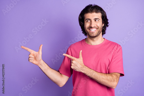 Photo of funny pretty young guy dressed pink outfit pointing looking empty space isolated purple color background