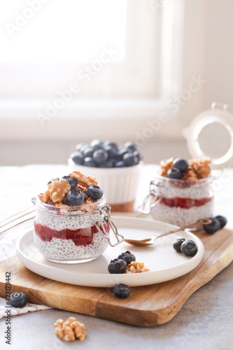 Chia seeds pudding with strawberry jam, granola, blueberry in glass jars 