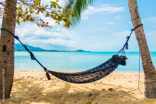 Empty hammock swing around beach sea ocean with white cloud blue sky