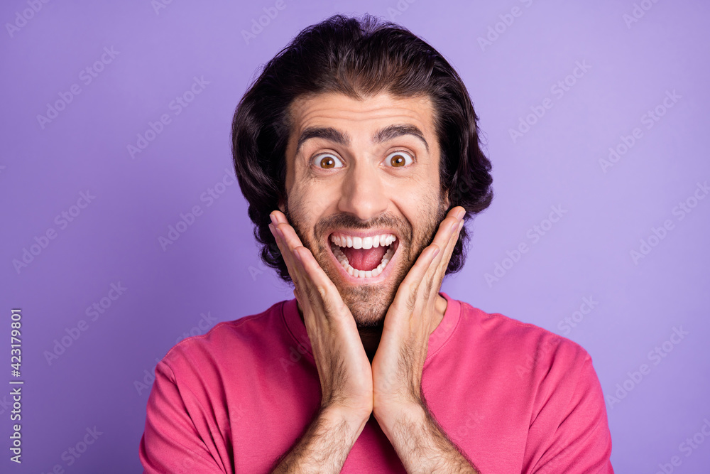 Photo of impressed nice brunet guy hands cheeks wear pink t-shirt isolated on pastel violet color background Photo of impressed nice brunet guy hands cheeks wear pink t-shirt isolated on pastel violet color background