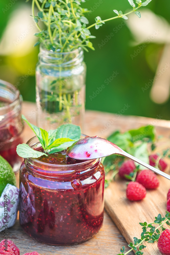 Raspberry jam and fresh raspberry on a rustic wooden table in the garden. Raspberry jam and fresh raspberry on a rustic wooden table in the garden.