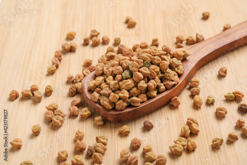 Dried chickpeas in wooden spoon on wooden background.