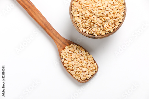 Unpolished Pigeon pea also known as toor dal in a bowl and spoon. Isolated on white background.