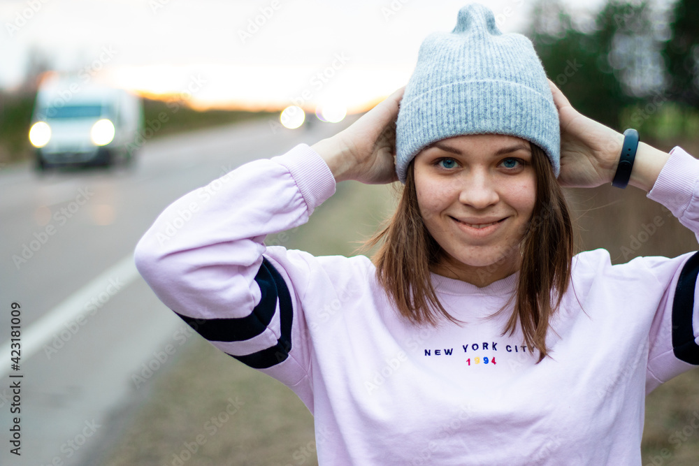smiling young woman standing on the road at sunset smiling young woman standing on the road at sunset