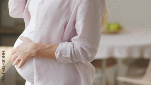 Wallpaper Mural Cheerful pregnant woman stroking her belly, smiling and speaking on mobile phone at home Torontodigital.ca