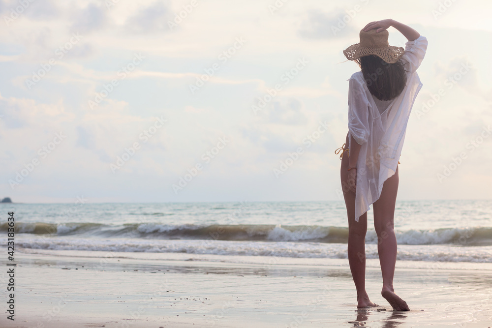 young woman in straw hat enjoying evening by the beach