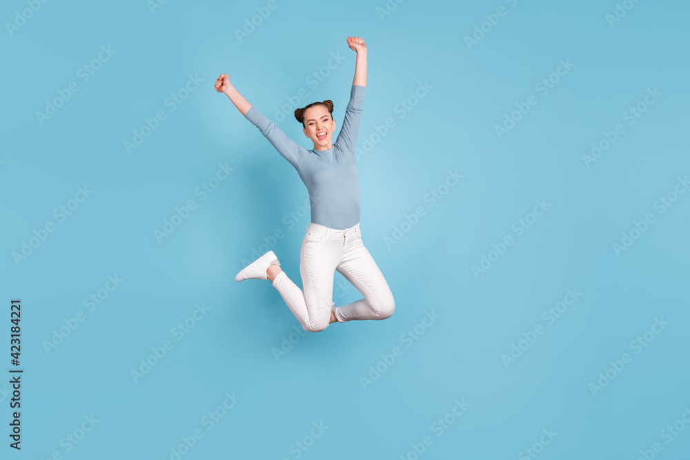 Full body photo of exited crazy happy woman jump up air raise hands win isolated on blue color background Full body photo of exited crazy happy woman jump up air raise hands win isolated on blue color background