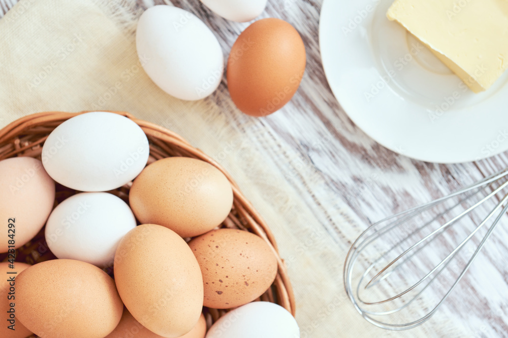 Eggs in basket, butter and whisk, top view, shallow depth of field, stylized Eggs in basket, butter and whisk, top view, shallow depth of field, stylized
