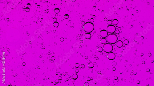 Oil bubbles on the water surface in motion, on a purple background, macro, splash screen, template, copy space