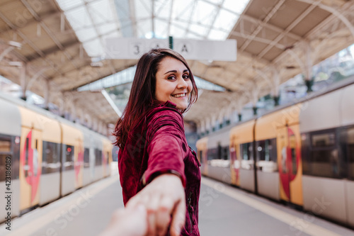 beautiful caucasian woman in train station waiting to travel. Holding hands with camera, follow me. Travel and lifestyle concept
