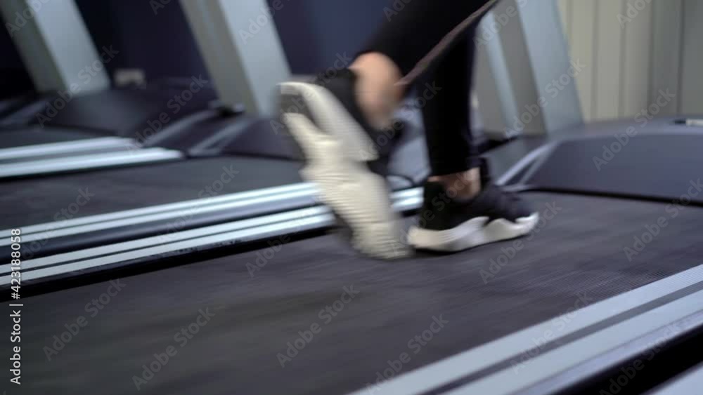 Female legs walking on treadmill, low angle view Female legs walking on treadmill, low angle view