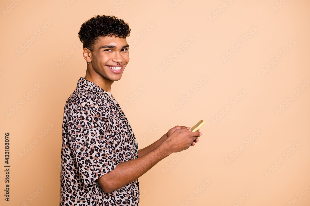 Profile portrait of handsome positive dark skin man toothy smile look camera isolated on beige color background Profile portrait of handsome positive dark skin man toothy smile look camera isolated on beige color background