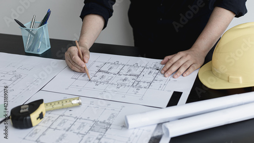 Architectural building design and construction plans with blueprints, Young man was designing a building or architecture with a ruler, pen, pencil, tape measure, architect hat.