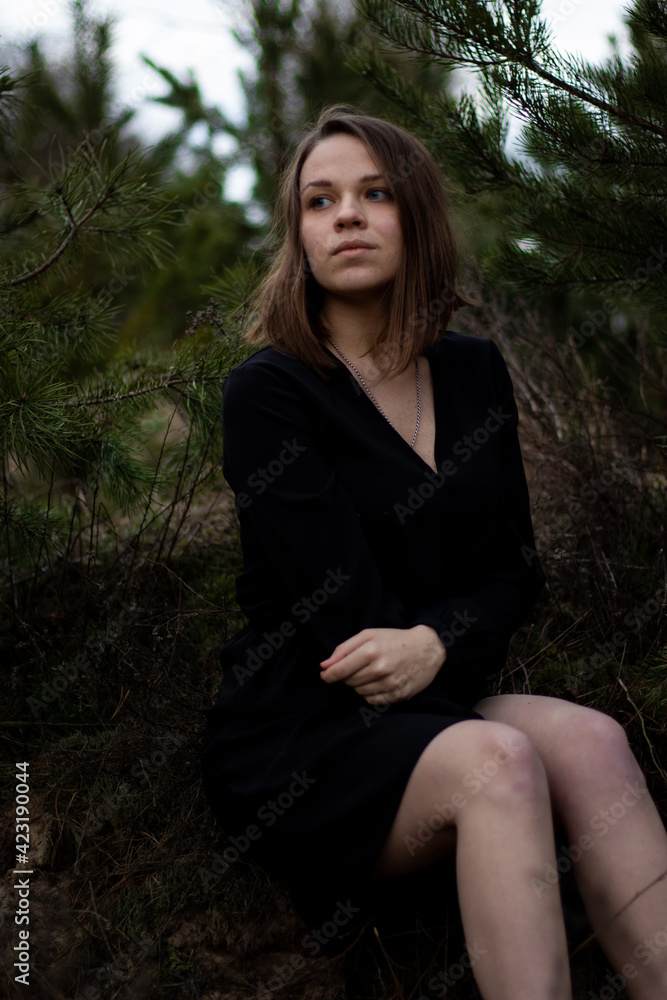 young brunette woman with short hair in a black dress near the pines young brunette woman with short hair in a black dress near the pines