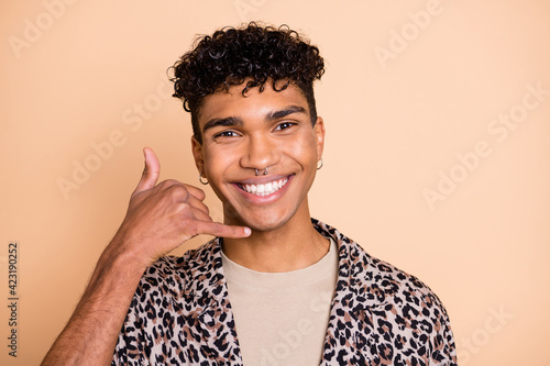 Portrait of brunet optimistic guy ask to call wear modern shirt isolated on pastel beige color background photo