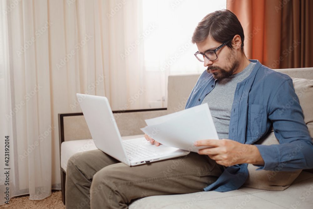 Entrepreneur works with a laptop and keeps a document in a home office Entrepreneur works with a laptop and keeps a document in a home office